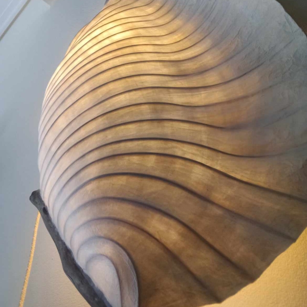 "Wing" is a wall-mounted sculpture capturing the graceful form and movement of a bird’s wing. Crafted from handmade paper, bamboo reed, and driftwood, it incorporates a fabric-covered electrical cord and porcelain socket for subtle illumination. Dimensions: 110 × 55 × 20 cm The piece evokes lightness and elegance, inviting viewers to reflect on flight and freedom.